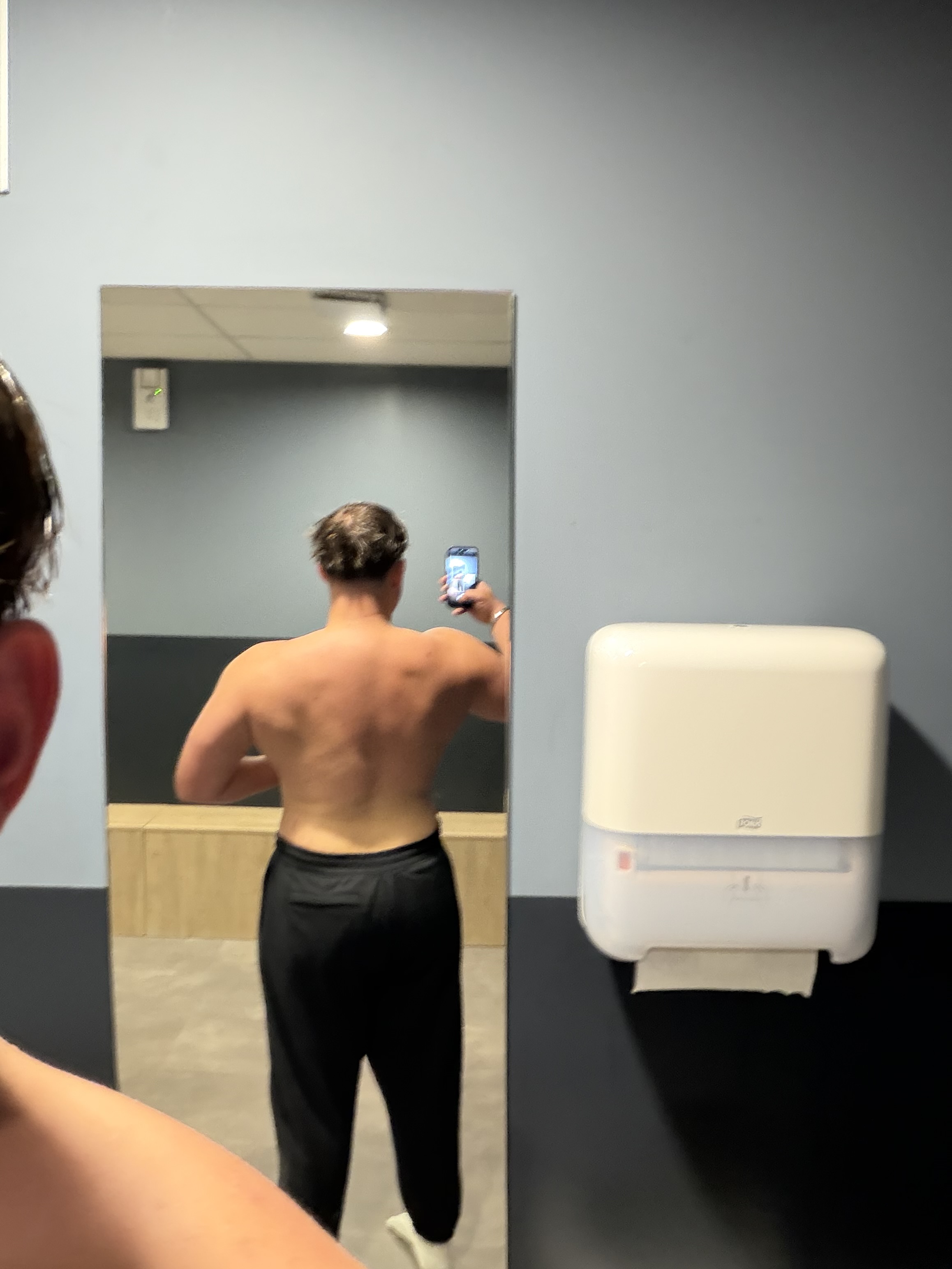 Tom photographie sa progression physique de dos dans un miroir